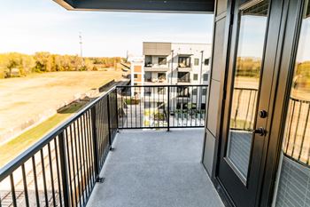 A balcony with a black railing and a view of a building and trees.